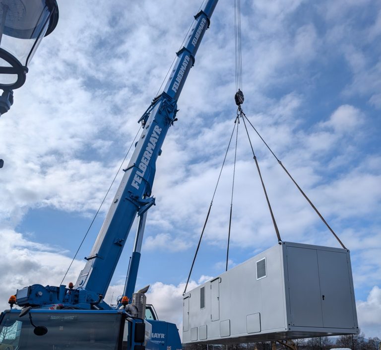 Container an Kran vor bewölktem Himmel